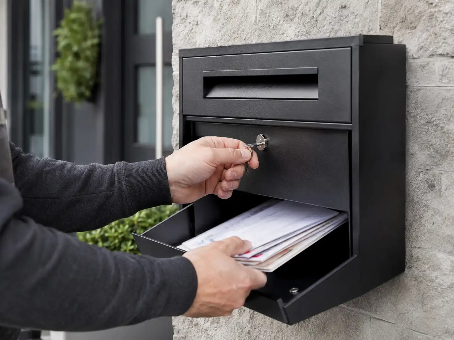 Homeowner using a key to open a locking mailbox and collect private mail securely